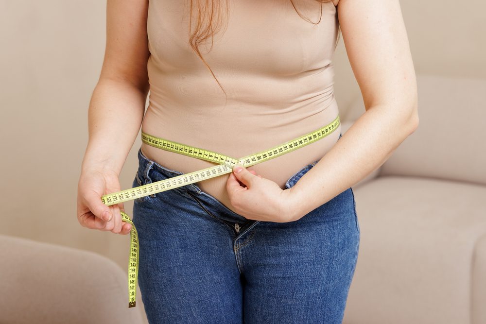 Close Up Of Woman Measuring Waist With Tape