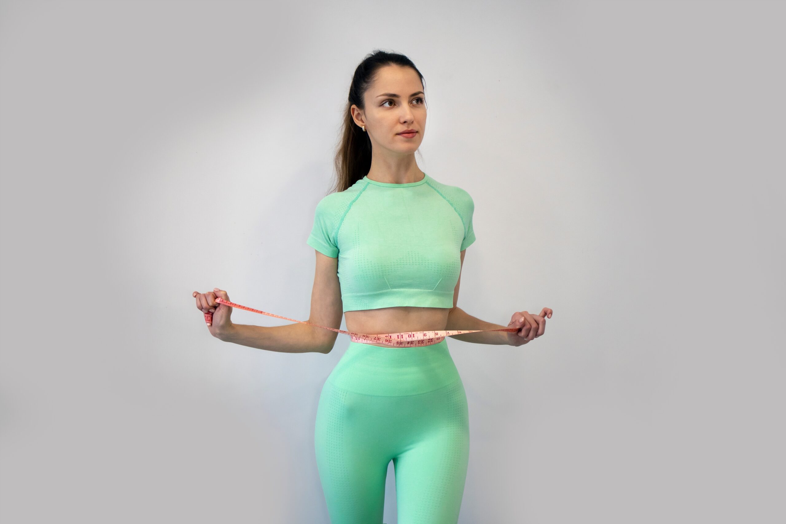 Young Slender Woman In sportswear Measuring Her Waist